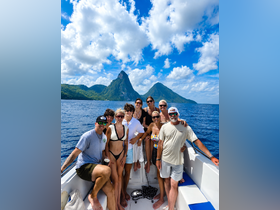 A cheerful group poses on a boat with stunning island scenery in the background, capturing the essence of a memorable day on the water.
