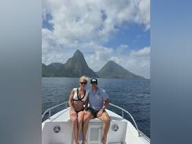 A couple enjoys a picturesque moment on a boat with stunning mountain scenery in the background, perfect for romantic getaways or adventure trips.