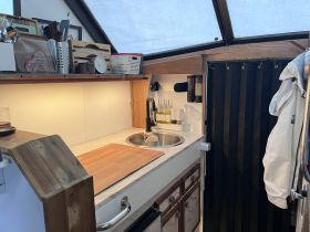 A cozy view of the boat's kitchen area featuring a sink and wooden countertop, perfect for meal preparation while on the water.