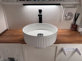 A modern sink setup in the cabin of a boat, featuring a stylish design and wooden countertop, ideal for onboard convenience.
