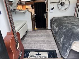 Cozy interior of a boat cabin featuring a comfortable seating area, helm, and welcoming decor — perfect for relaxing on the water.