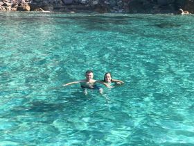 A couple enjoys a refreshing swim in crystal-clear waters, capturing the essence of a perfect day on the water.