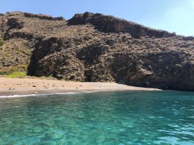 A stunning view of a secluded beach surrounded by rocky cliffs and clear turquoise waters, perfect for a tranquil getaway or exploration.