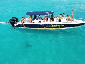 A lively group enjoys a day on the water aboard the Suneeta, showcasing fun and relaxation in the beautiful turquoise sea.