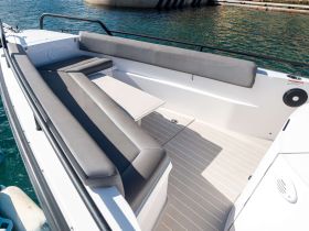A spacious and modern seating area inside a boat, featuring comfortable cushions and a sleek design, perfect for relaxing while on the water.