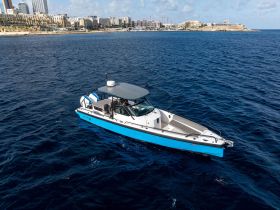 A sleek speedboat navigates the deep blue waters, showcasing its modern design against a backdrop of coastal architecture — perfect for thrilling day trips or leisurely cruises.