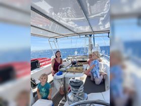 A family enjoys a meal inside the cabin of a sailboat, showcasing a cozy atmosphere with children engaged in the experience.
