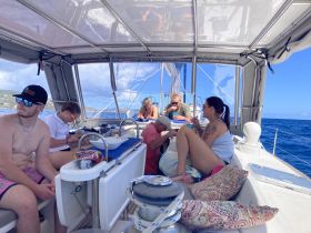 A lively group enjoys their time aboard a sailboat, engaging in activities and savoring the beautiful ocean views — perfect for a memorable sailing adventure.