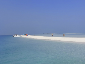 Guests enjoy a sunny day at a picturesque sandbar, with a boat anchored nearby — perfect for swimming and relaxation in crystal-clear waters.
