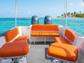 Interior view of a boat featuring bright orange seating and a clean helm area, perfect for comfortable cruising on the water.