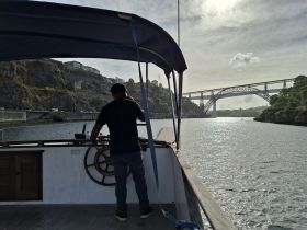 A captain navigates a boat along a scenic river, with a stunning bridge in the background — perfect for exploring picturesque waterways.