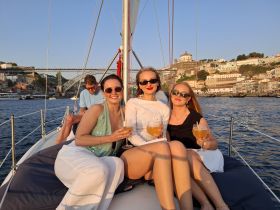 A group of friends enjoys cocktails on a yacht at sunset, capturing the essence of a perfect evening on the water with stunning views of the city.