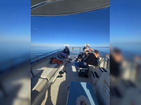Inside view of a boat's seating area with guests relaxing, showcasing a comfortable space for enjoying time on the water.
