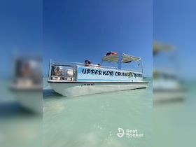 A well-lit shot of the 'Upper Keys Cruises & Tours' boat anchored in clear waters, showcasing its vibrant design and inviting atmosphere for cruising adventures.
