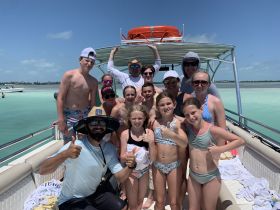 A joyful group of family and friends poses on a pontoon boat, enjoying a sunny day on the water — perfect for memorable outings and celebrations.