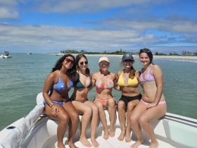 A fun group of friends enjoys a sunny day on the boat, showcasing their vibrant bikinis and smiles — perfect for summer adventures on the water.