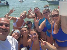 A lively group of friends celebrates together in the water, showcasing the joy of summer fun and camaraderie on a boating trip.