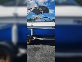 A clear side view of a boat with a sleek design, showcasing its blue hull and protective canopy, perfect for enjoying time on the water.