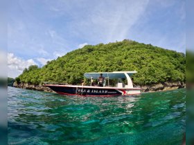 A scenic view of a boat excursion near a lush island, showcasing guests enjoying their time on the water — perfect for adventure seekers and nature lovers.