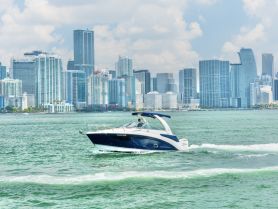 A sleek yacht cruises through the vibrant waters of Miami, with a stunning city skyline in the backdrop — an ideal scene for boating enthusiasts and urban explorers.