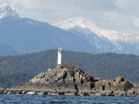 A stunning view of a lighthouse perched on a rocky outcrop, surrounded by majestic mountains — a picturesque landmark perfect for nature lovers and boating enthusiasts.