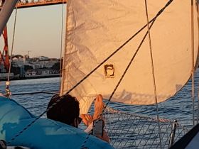 A serene moment aboard a sailboat as a guest relaxes and enjoys the view during sunset, capturing the essence of a perfect sailing experience.