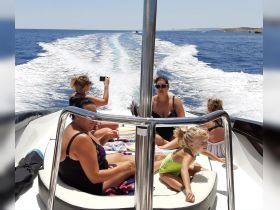 A joyful group enjoys a sunny day on a boat, capturing memories and having fun — perfect for family outings or summer adventures on the water.
