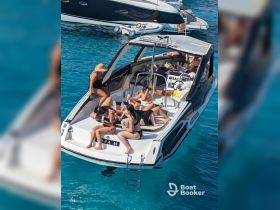 A lively group enjoys a day on a yacht, relaxing and sipping cocktails in the crystal-clear waters — the perfect setting for a summer party.