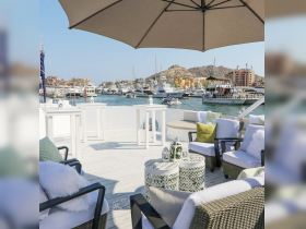 A beautifully arranged lounge area on a boat, featuring comfortable seating and an umbrella, perfect for relaxing while enjoying views of the marina.
