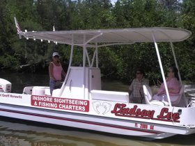 A group enjoys a leisurely moment aboard the 'Lindsay Lee' boat, perfect for inshore sightseeing and fishing charters in a scenic waterway.