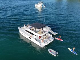 A lively scene featuring a group enjoying paddleboarding and a water slide off a luxurious yacht, perfect for summer fun on the water.