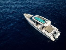 Aerial view of a sleek speedboat cruising through deep blue waters, showcasing its modern design and spacious deck — perfect for thrilling adventures on the water.