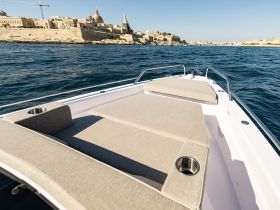A stunning view of the front deck of a yacht, showcasing comfortable seating and a picturesque backdrop of the coastline, perfect for leisurely outings on the water.