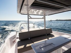 A stylish interior view of a boat's seating area, showcasing comfortable lounge space and a sleek helm — perfect for relaxing while cruising the open waters.
