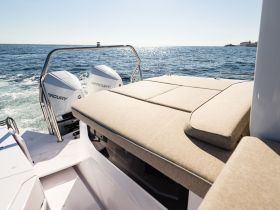 A sleek interior view of a boat's seating area, showcasing comfortable cushions and the powerful Mercury engines in the background, perfect for a day on the water.