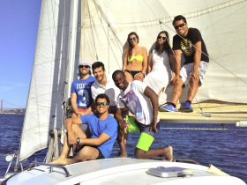 A cheerful group of friends enjoys a sailing adventure, capturing the joy of their experience on the water with stunning views in the background.