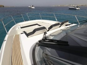 A stunning view of a yacht's bow, showcasing sleek design and luxurious seating against a backdrop of clear blue waters.