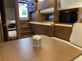 Interior view of a modern boat cabin featuring elegant wood finishes and a cozy seating area, perfect for relaxing during trips on the water.