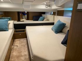 A cozy interior view of a boat cabin featuring comfortable seating and decorative pillows, perfect for relaxation while on the water.