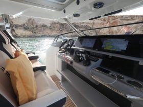 A sleek view of the helm area inside a modern boat, showcasing the console and seating, perfect for navigating the open waters.