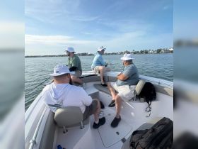 A group of friends enjoys a day of fishing on a boat, soaking up the sun and good company — perfect for a memorable outing on the water.