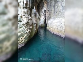 A stunning view of a secluded cave with crystal-clear waters, perfect for exploring hidden gems along the coastline.