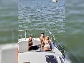 A fun group enjoys drinks on the deck of a catamaran, soaking up the sun and good vibes on the water.