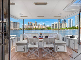 A stylish interior view of a yacht's lounge area, featuring comfortable seating and a stunning backdrop of city skyscrapers along the waterfront.