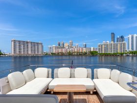 A spacious lounge area on a yacht featuring comfortable seating, perfect for relaxing while enjoying views of the city skyline.