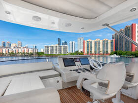 A sleek interior view of a boat's helm area, showcasing modern seating and controls with a vibrant city skyline in the background, perfect for luxury cruising.