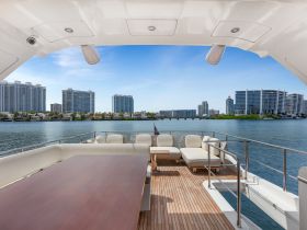 A spacious and elegantly designed lounge area on a yacht, featuring comfortable seating and a beautiful view of the waterfront skyline.