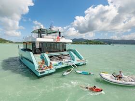 A lively scene featuring a group enjoying a day on a luxurious yacht, with activities like swimming and jet skiing in the beautiful turquoise waters.