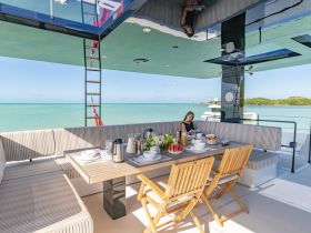 A beautifully arranged dining area on a luxury yacht, featuring a woman enjoying a meal with stunning ocean views — perfect for relaxing meals at sea.