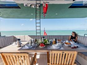 A beautifully arranged dining area on a yacht, featuring a woman enjoying a meal with stunning ocean views — perfect for luxurious onboard dining experiences.